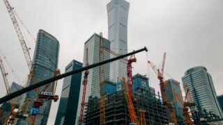 a large group of cranes standing in front of a tall building